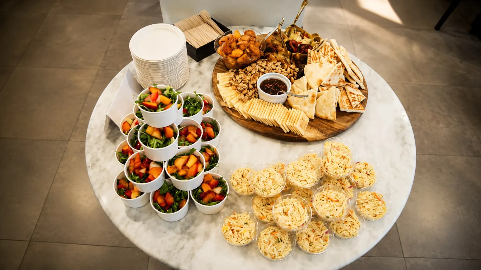 A styled cheese board with salad cups and mini quiches